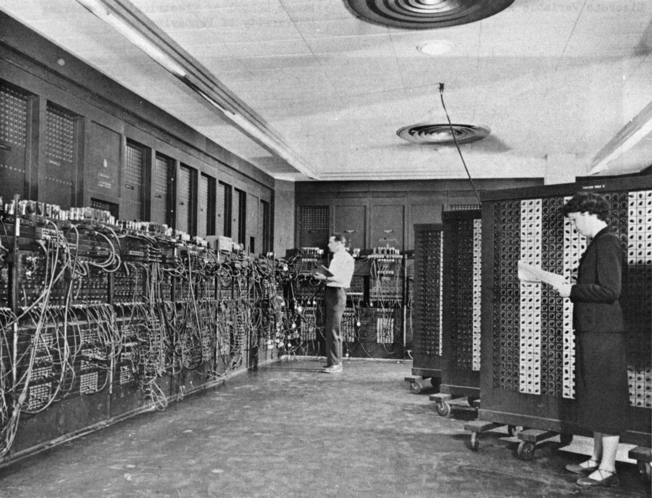 Phòng máy ENIAC với những dãy tủ đầy dây cáp và hai người đang vận hành